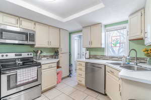 Kitchen featuring light tile patterned flooring, appliances with stainless steel finishes, sink, and a textured ceiling