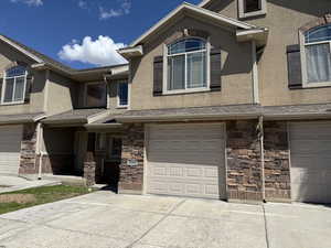 Townhome / multi-family property featuring stucco siding, stone siding, and a garage