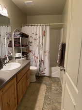 Full bathroom featuring vanity, shower / bathtub combination with curtain, and toilet