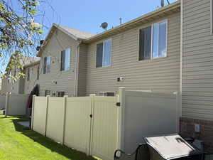 View of home's exterior with a yard, fence, and a gate