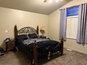 Carpeted bedroom with ceiling fan and vaulted ceiling