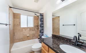 Full bathroom featuring vanity, shower / bath combo, and toilet