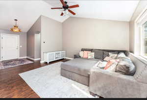 Living room with ceiling fan, dark hardwood / wood-style floors, and vaulted ceiling