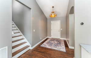 Foyer with dark hardwood / wood-style flooring and lofted ceiling