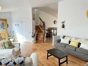 Living room with high vaulted ceiling and light hardwood / wood-style floors