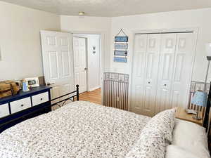 Bedroom with a closet, a textured ceiling, and light wood-type flooring