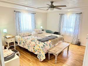 Bedroom with hardwood / wood-style flooring, ceiling fan, and a textured ceiling