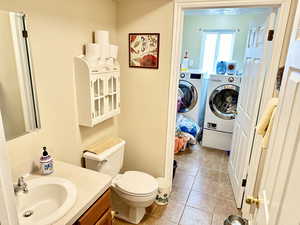 Bathroom with separate washer and dryer, vanity, tile patterned flooring, and toilet