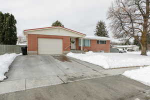 Ranch-style house with driveway, brick siding, an attached garage, and fence