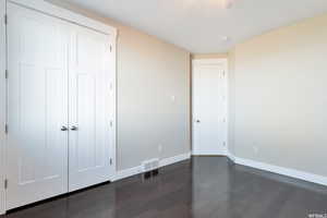 Unfurnished bedroom with dark wood-type flooring and a closet