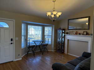 Entryway with a notable chandelier, hardwood flooring, and vaulted ceiling