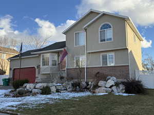 View of front of home featuring a garage, rock and perennial landscaping