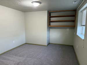 Carpeted empty room featuring a textured ceiling