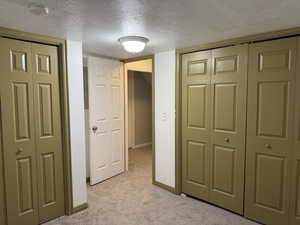 Corridor featuring light carpet and a textured ceiling