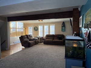 Living room featuring beam ceiling, plenty of natural light, a textured ceiling, and carpet