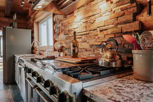 Kitchen featuring wooden ceiling, light countertops, appliances with stainless steel finishes, rustic walls, and beam ceiling