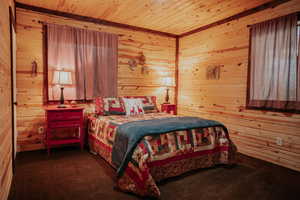 Bedroom with wood ceiling, wooden walls, and carpet flooring