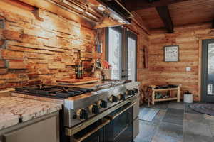 Kitchen featuring log walls, double oven range, wood ceiling, french doors, and beam ceiling