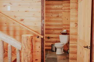 Half bathroom featuring toilet and rustic walls