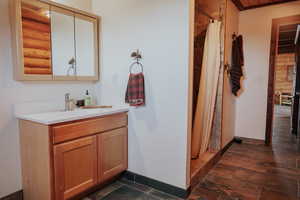 Full bath featuring stone finish floor, vanity, baseboards, and a shower with curtain