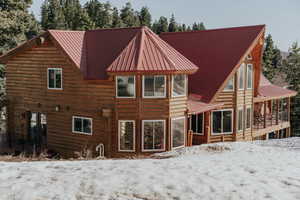 Snow covered property featuring metal roof, french doors, and a sunroom