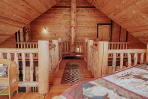 Unfurnished bedroom featuring wooden ceiling, wooden walls, wood-type flooring, and vaulted ceiling