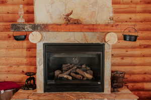 Room details with log walls and a stone fireplace