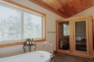 Bathroom featuring wood finished floors, wooden ceiling, a soaking tub, and vaulted ceiling