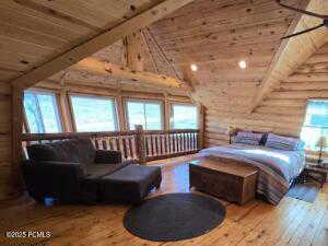 Bedroom with high vaulted ceiling, hardwood / wood-style floors, log walls, and wood ceiling