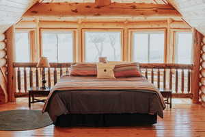 Bedroom featuring light wood-style flooring, log walls, and vaulted ceiling