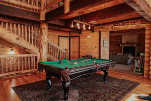 Recreation room featuring beamed ceiling, a fireplace, wood finished floors, log walls, and billiards