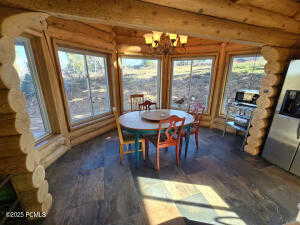 Dining room with dark hardwood / wood-style floors, log walls, an inviting chandelier, and beamed ceiling