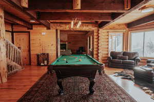 Recreation room featuring pool table, wood finished floors, beam ceiling, and rustic walls