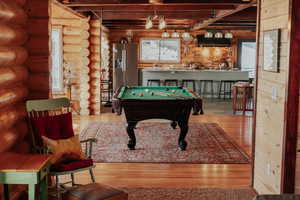 Game room featuring log walls, hardwood / wood-style floors, and pool table