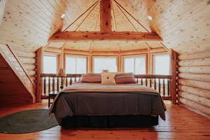 Bedroom featuring light wood-style flooring, wooden ceiling, and rustic walls
