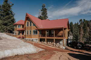 Back of house with metal roof and log exterior