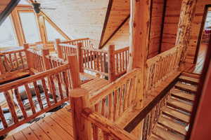 Stairs with wood walls, a ceiling fan, and hardwood / wood-style flooring