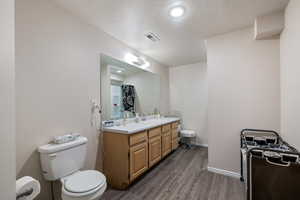 Bathroom with hardwood / wood-style floors, a textured ceiling, vanity, and toilet