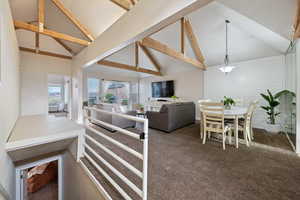 Carpeted living room with high vaulted ceiling and beam ceiling