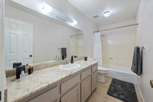 Full bathroom with tile patterned floors, shower / bathtub combination with curtain, toilet, and vanity