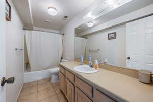 Full bathroom featuring toilet, shower / bath combo, tile patterned flooring, and vanity