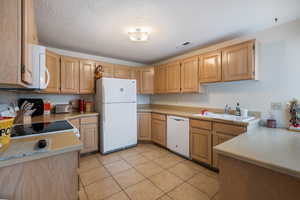 Kitchen featuring light tile patterned flooring, sink, white appliances, and light brown cabinets