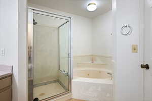 Bathroom featuring plus walk in shower, garden tub and vanity