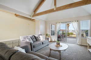 Carpeted living room featuring lofted ceiling with beams