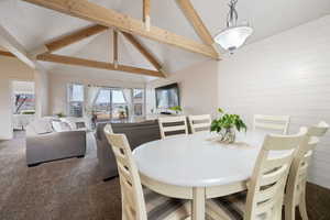 Dining space featuring carpet and vaulted ceiling with beams