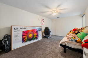 Bedroom featuring a textured ceiling, a closet, carpet flooring, and ceiling fan