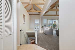 Corridor featuring high vaulted ceiling, beamed ceiling, and light colored carpet