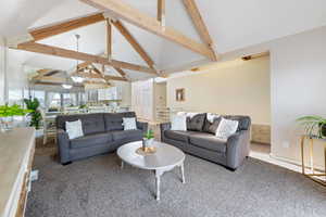 Carpeted living room with high vaulted ceiling and beamed ceiling