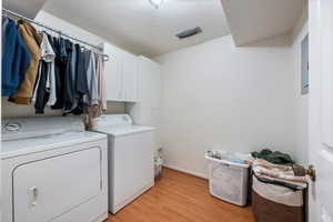 Laundry room featuring washing machine and dryer, cabinets, a textured ceiling, and light hardwood / wood-style floors