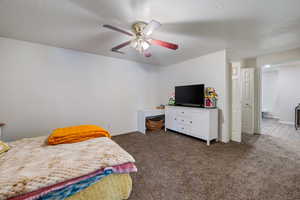 Bedroom with ceiling fan, dark colored carpet, and a textured ceiling